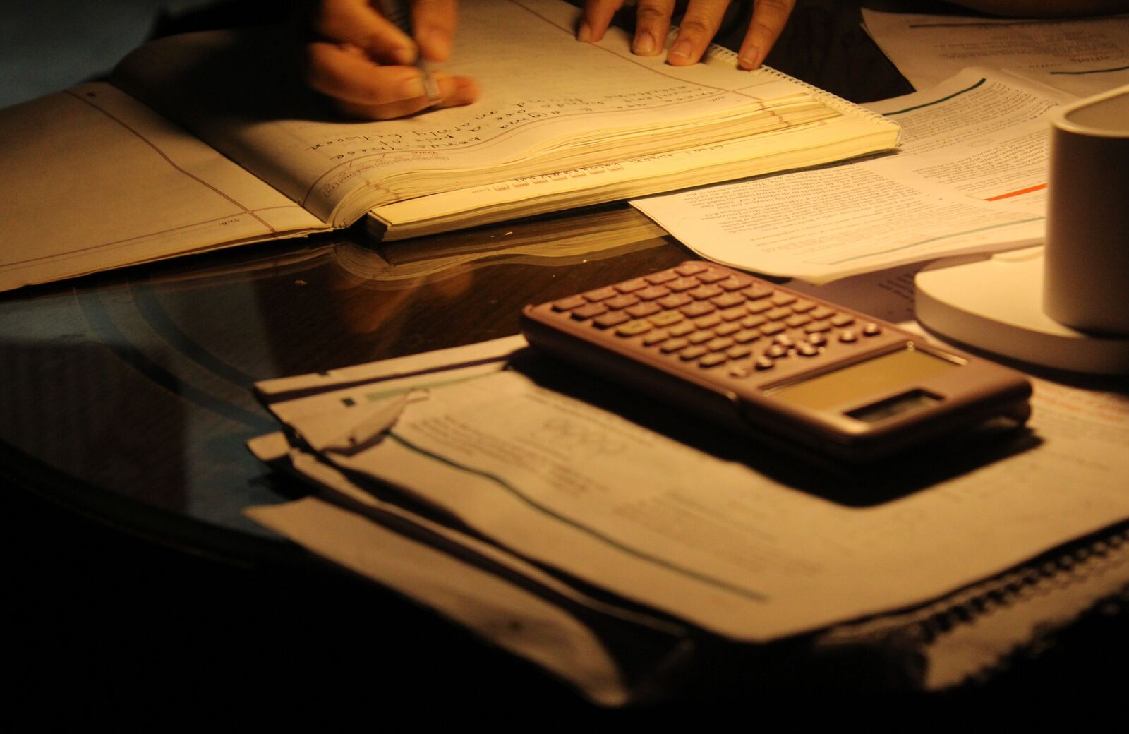 Soumission de construction préparée à la main le soir, avec calculatrice et documents papier